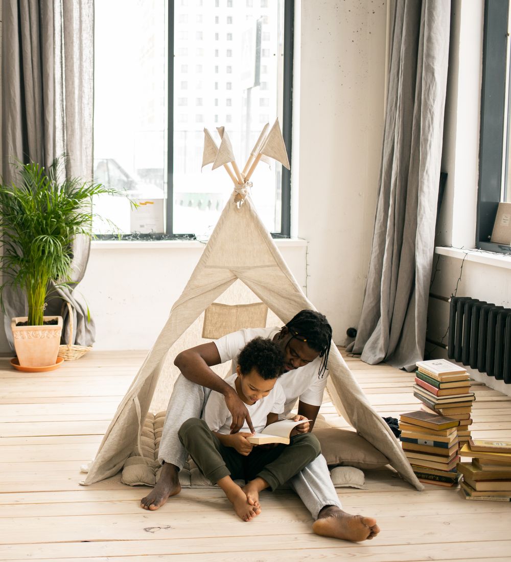 Two parents sitting on the floor helping their children with homework and writing on a blackboard