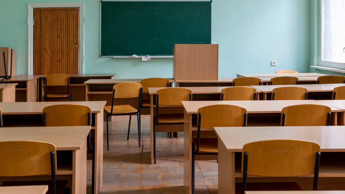 An empty classroom with rows of desks facing a chalkboard